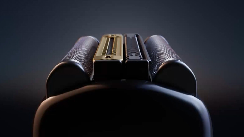 Nahaufnahme des Scherkopfs des Braun Nevo Rasierers vor dunklem Hintergrund. Im Fokus stehen die präzisen Scherelemente mit einem goldfarbenen und einem schwarzen Mittelteil, die das hochwertige Design und die innovative Rasiertechnologie hervorheben.