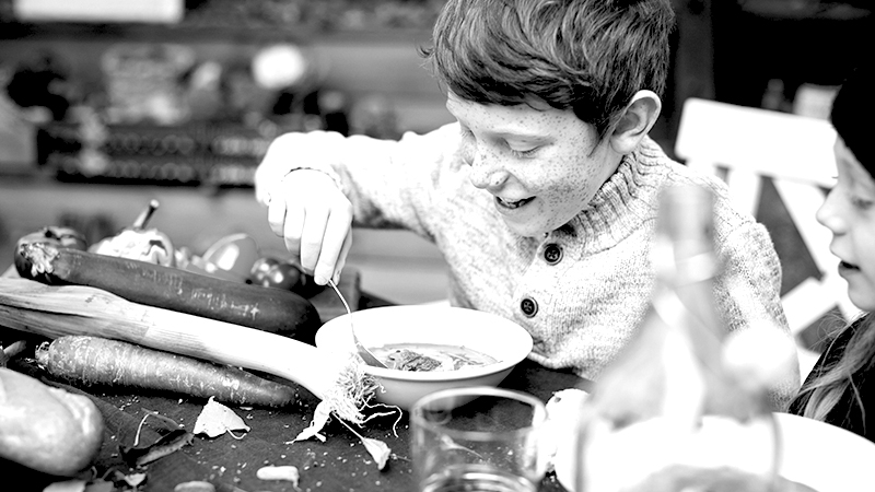 Ein Junge mit Sommersprossen isst eine Suppe.